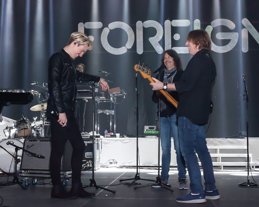 Geordie Brown, Kelly Hansen, and Jeff Pilson laugh on stage during sound check. 